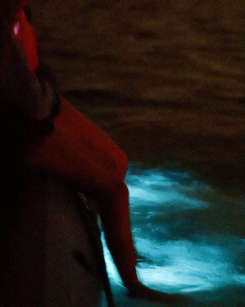 Child’s feet glowing in bioluminescent water during a family rafting tour near Cocoa Beach, Florida