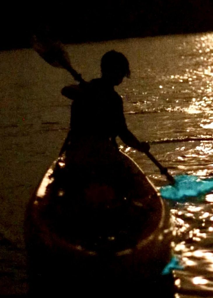 Kayaker paddling through glowing bioluminescent waters on Florida’s Space Coast at night.jpg